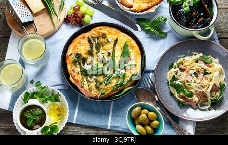 Italian cuisine on rustic wooden table. Different types of pizza, pasta, snacks and capreze. Healthy homemade food. Stock Photo