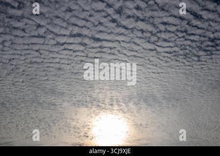 Sun shining through altocumulus cloud cover Stock Photo