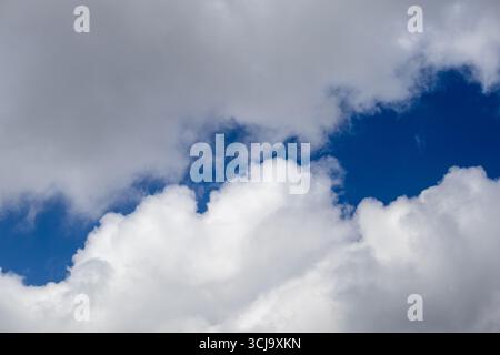 White cumulus clouds with patches of blue sky Stock Photo