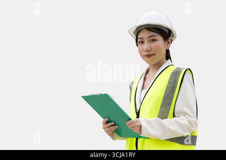 Portrait Asian young women engineer builder in safety vest hardhat handle checklist happy smiling isolated on white background with clipping path Stock Photo