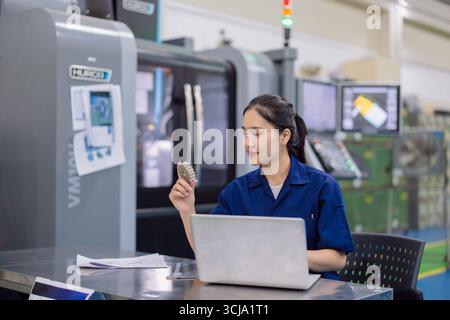 young technician engineer metal part designer worker with CNC lathe metal machine in modern steel industry factory Stock Photo