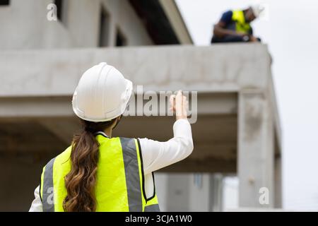 Construction engineer woman foreman, leader supervisor control operate construction worker team working with new house project Stock Photo