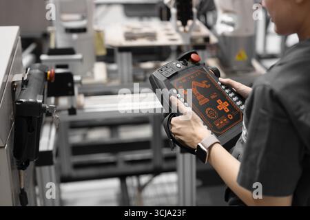 Closeup engineer using industry robot setup operate control by remote control in modern plant factory Stock Photo