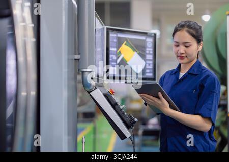 young technician engineer worker women working with CNC lathe metal machine in modern steel industry factory Stock Photo