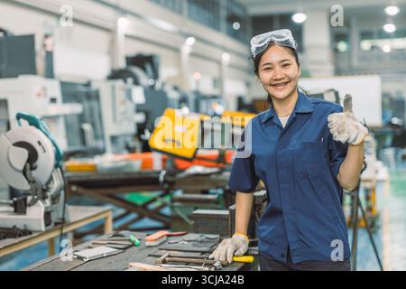 happy smiling engineer worker standing portrait thumbs up in modern metal workshop plant factory Stock Photo