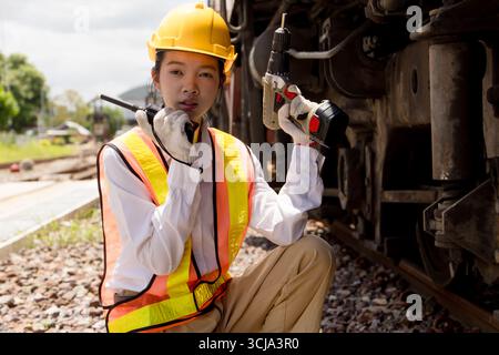 Asian young teen engineer worker work in Train station, Old locomotive service maintenance work engine under car locomotive checkup maintenance Stock Photo