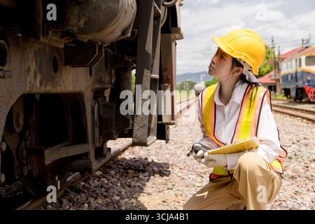Asian young teen engineer worker work in Train station, Old locomotive service maintenance work engine under car locomotive checkup maintenance Stock Photo