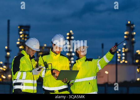 Group of Engineers team night shift working oil and gas refinery service, Workers hard work at night petroleum industry plant background. Stock Photo