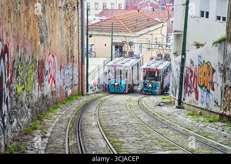 Lisbon, Portugal - 29.12.2022: A Colorful Tram Navigating Through a Vibrant Urban Alley Adorned with Stunning Graffiti Art Stock Photo