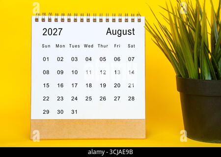 August 2027 calendar template on a yellow-framed background featuring organized date grid and plant accessory Stock Photo - Alamy