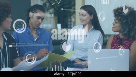 Four team members reviewing and discussing project in meeting room with yellow folder and charts Stock Photo