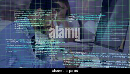 Software developers reviewing code on monitor at office desk, with keyboard, mouse and laptop Stock Photo