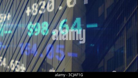 Displaying LED ticker display showing cyan and blue stock prices over office facade, metal mullions Stock Photo