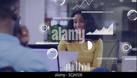 Presenting Hispanic woman holding printed reports at office desk, with laptop and data overlays Stock Photo