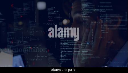 Mid-adult man focusing on code on monitor in home office, with laptop keyboard glasses reflection Stock Photo