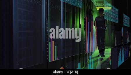 Analyzing Korean IT engineer reviewing data on tablet in server corridor, with holographic charts Stock Photo