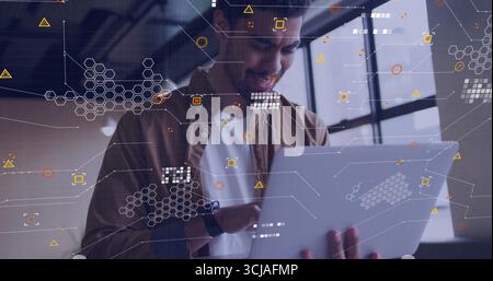 Tech professional holding silver laptop displaying overlaid data graphics in office with smartwatch Stock Photo