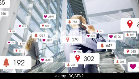Riding escalator businessman checking smartphone in office atrium, with floating notifications Stock Photo