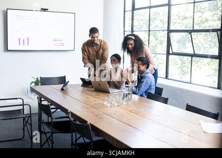 Diverse business team collaborating on laptops during office meeting, sharing ideas Stock Photo