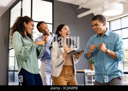 Diverse business team celebrating success with tablet in modern office Stock Photo