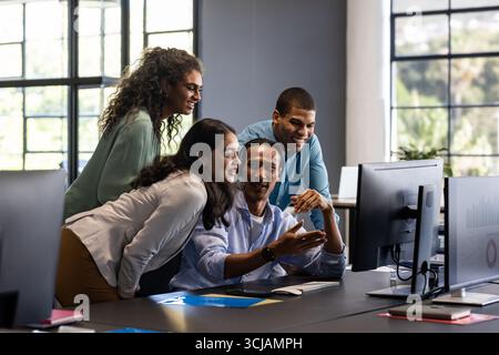 Collaborating in office, diverse team discussing project ideas around computer Stock Photo