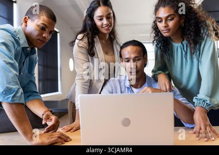 Diverse business team collaborating on laptop project in modern office setting Stock Photo