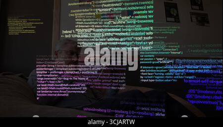 Working man typing code on laptop on leather couch in living room, with projected code snippets Stock Photo