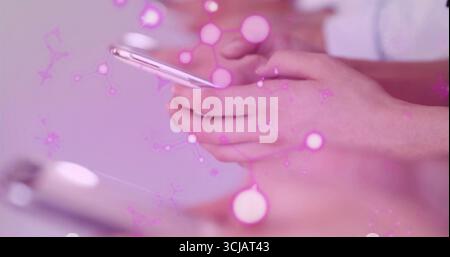 Colleagues' hands tapping and holding white and silver phones on desk, with purple-pink overlay Stock Photo