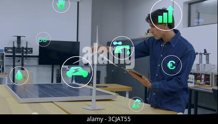 Male engineer holding tablet, adjusting wind turbine and solar panel prototype at lab, with metrics Stock Photo