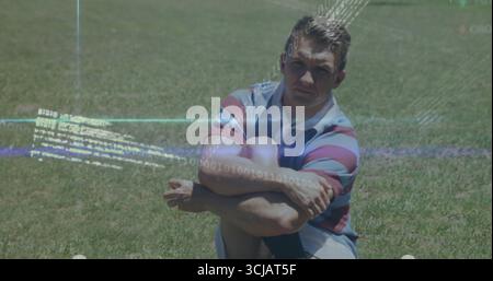 Sitting man hugging knees cross-legged on grass field, wearing striped shirt and light shorts Stock Photo