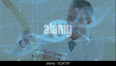 Examining scientist in lab coat holding spine and DNA models in lab, with holographic data Stock Photo