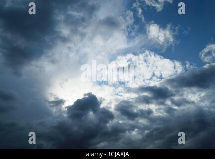The sun is shining behind the rain cumulus clouds high in the sky Stock Photo
