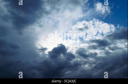 The sun is shining behind the rain cumulus clouds high in the sky Stock Photo