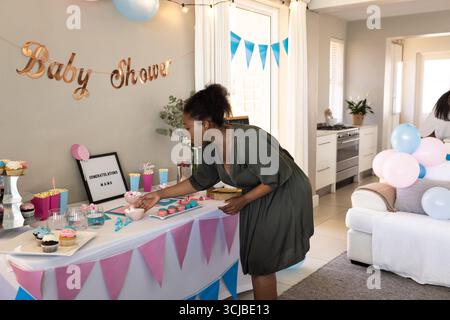 Woman decorating table with cupcakes and gifts at home baby shower celebration Stock Photo