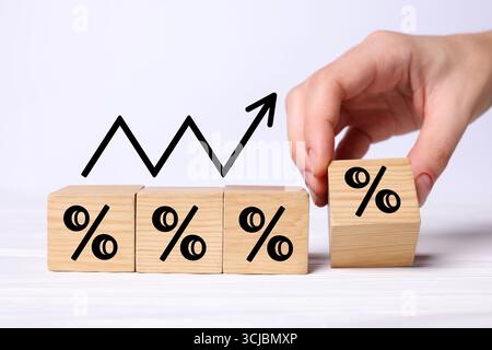 Man holding wooden cube with percent sign at white table, closeup Stock Photo