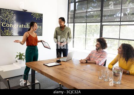 In conference room, diverse business team discussing achievements and celebrating success Stock Photo