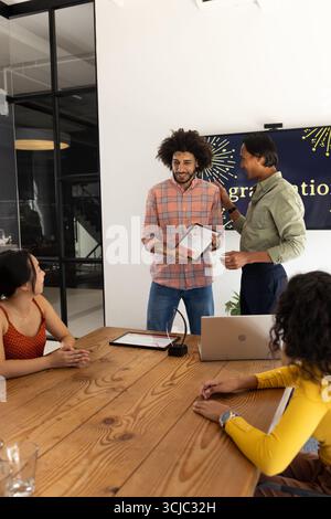 Diverse business team discussing project with tablet and laptop in modern office Stock Photo