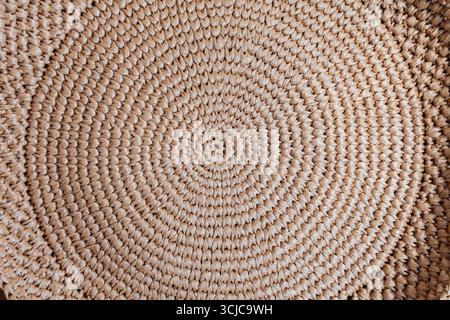 Circular weaving from natural brown raffia, close-up. Stock Photo
