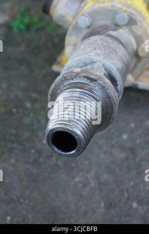 closeup of end of metal pipe with external screw threading as part of heavy machinery component against blurry background in soft focus in outdoor Stock Photo