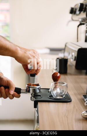 A close-up image showcases hands preparing fresh coffee grounds for an espresso machine in a modern coffee shop, highlighting the art and precision of Stock Photo