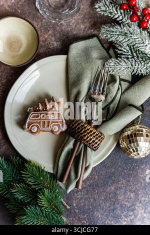 Elegant Christmas table setting featuring a gingerbread cookie on a plate with green napkin, utensils, and a wreath, creating a cozy holiday atmospher Stock Photo