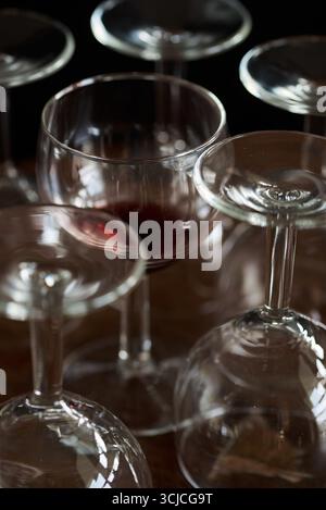 A selection of wine glasses, some filled and some empty, arranged elegantly on a dark wooden table. The soft lighting highlights the glass texture bea Stock Photo