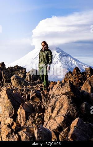 A hiker explores a rocky terrain with the majestic snow-capped Iztaccihuatl volcano in the background, showcasing the beauty and adventure of mountain Stock Photo