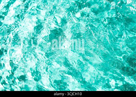 A close-up view of turquoise pool water, capturing the shimmering textures and dynamic patterns formed by sunlight reflecting off the rippled surface Stock Photo