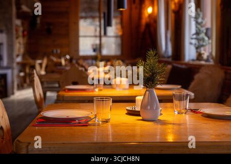 Warm, inviting interior of an alpine restaurant in Austria during winter. Wooden decor, elegant table settings, and festive atmosphere create a charmi Stock Photo