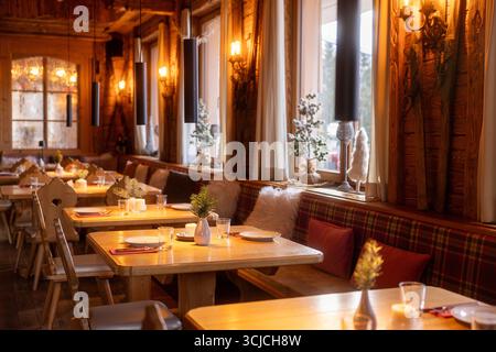 A charming interior of an Alpine restaurant in Austria, beautifully decorated for winter. Warm lighting highlights the wooden furniture and festive de Stock Photo