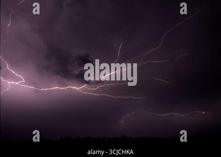 A dramatic display of a lightning storm illuminating the night sky with electric bolts. The dark, overcast clouds create a powerful contrast against t Stock Photo