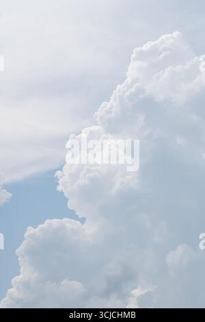 A beautiful view from below of white, fluffy clouds floating peacefully against a serene blue sky. The image exudes tranquility and simplicity in natu Stock Photo