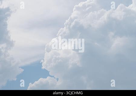 Fluffy white clouds rise majestically against a bright blue sky, creating a serene and peaceful atmosphere. The billowing forms convey a sense of calm Stock Photo