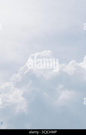 A serene view of soft, billowing clouds against a bright blue sky, capturing the ethereal beauty and peacefulness of nature from below. Perfect for ba Stock Photo